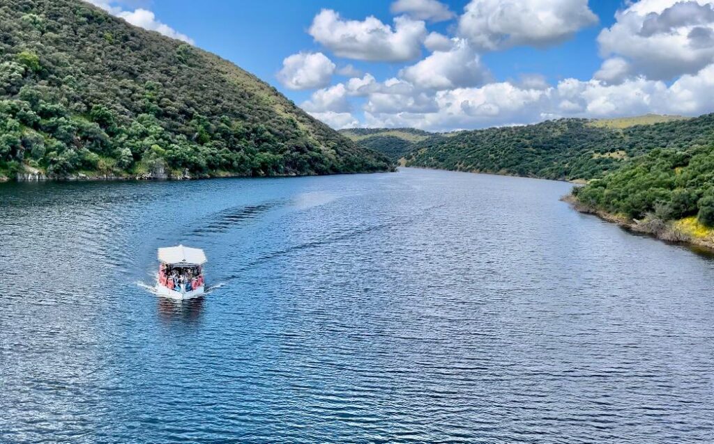 Barco navegando entre grandes formaciones rocosas en el río Tajo, en Monfragüe.