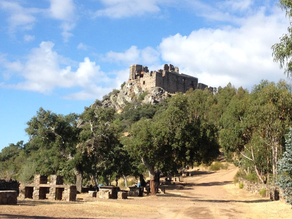 Castillo_Mirabel_1 Castillo de Mirabel situado sobre una colina rodeada de vegetación y caminos rurales.