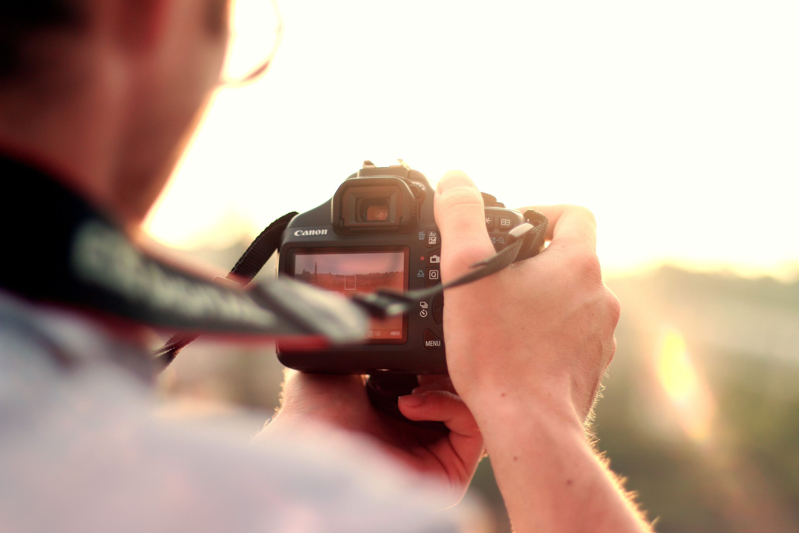 Persona fotografiando un paisaje al atardecer con una cámara.