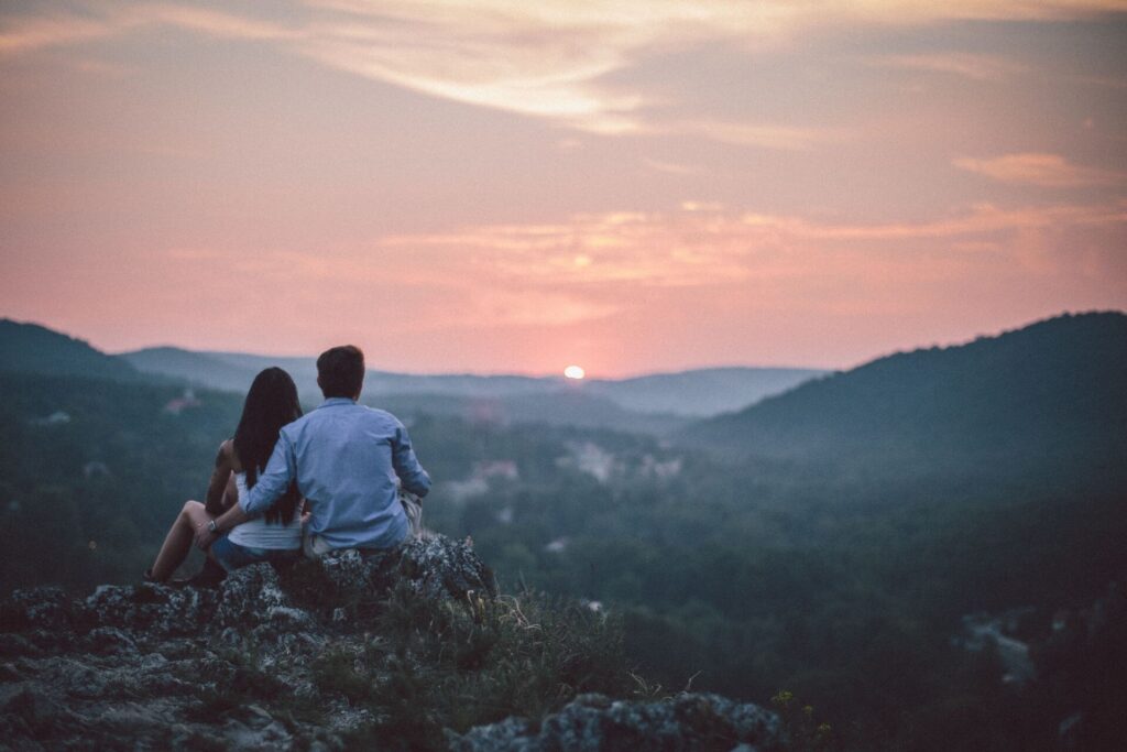 Pareja contemplando juntos el atardecer desde un mirador en un paisaje natural.