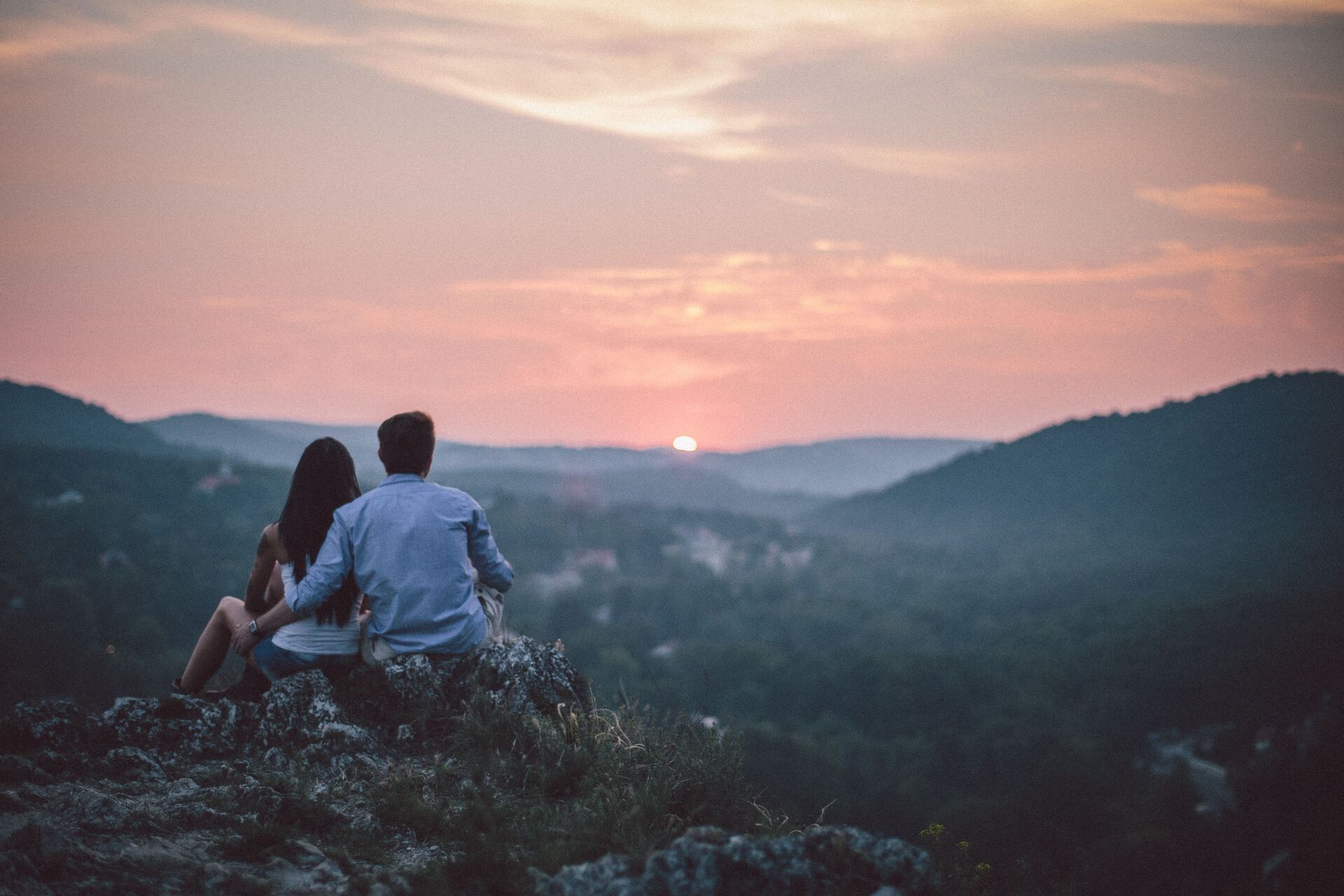 Pareja contemplando juntos el atardecer desde un mirador en un paisaje natural.